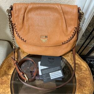 MCM shoulder bag in a tan or cognac featuring gathered flap and whipstitch trim